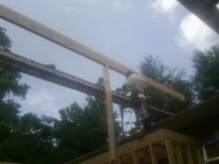 Carpenter setting a ridge beam over a new addition frame — Ice Dam Removal by Roofing Brothers in Santa Claus