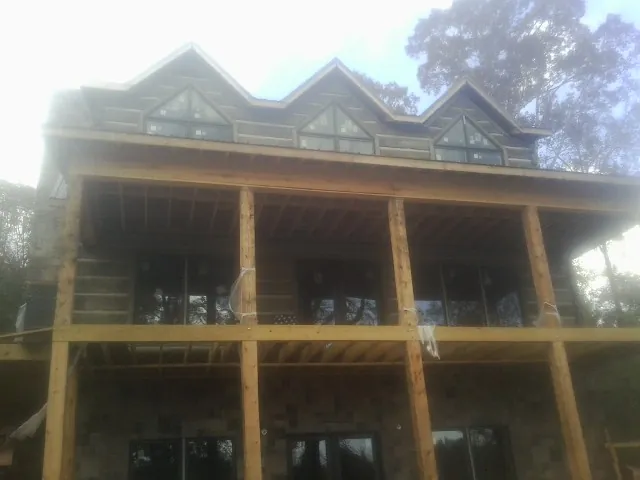 Dormers and porch framing on a large log home under construction — Roof Coating work by our crew in Santa Claus
