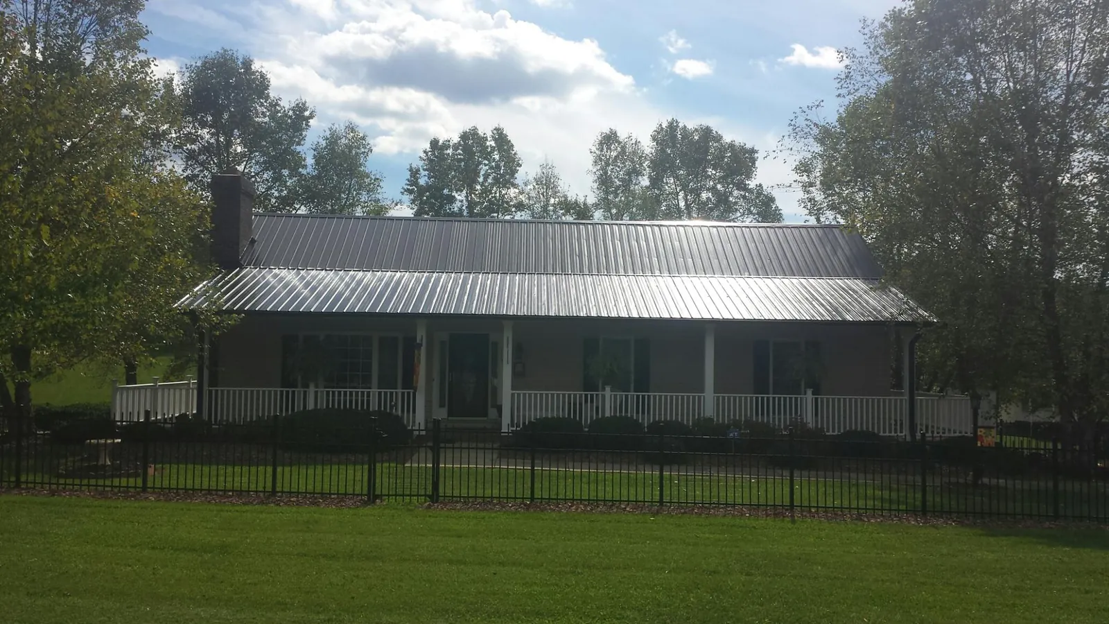 Gray metal roof on a brick ranch with a full width front porch — Gutter Guard Installation work by our crew in Santa Claus