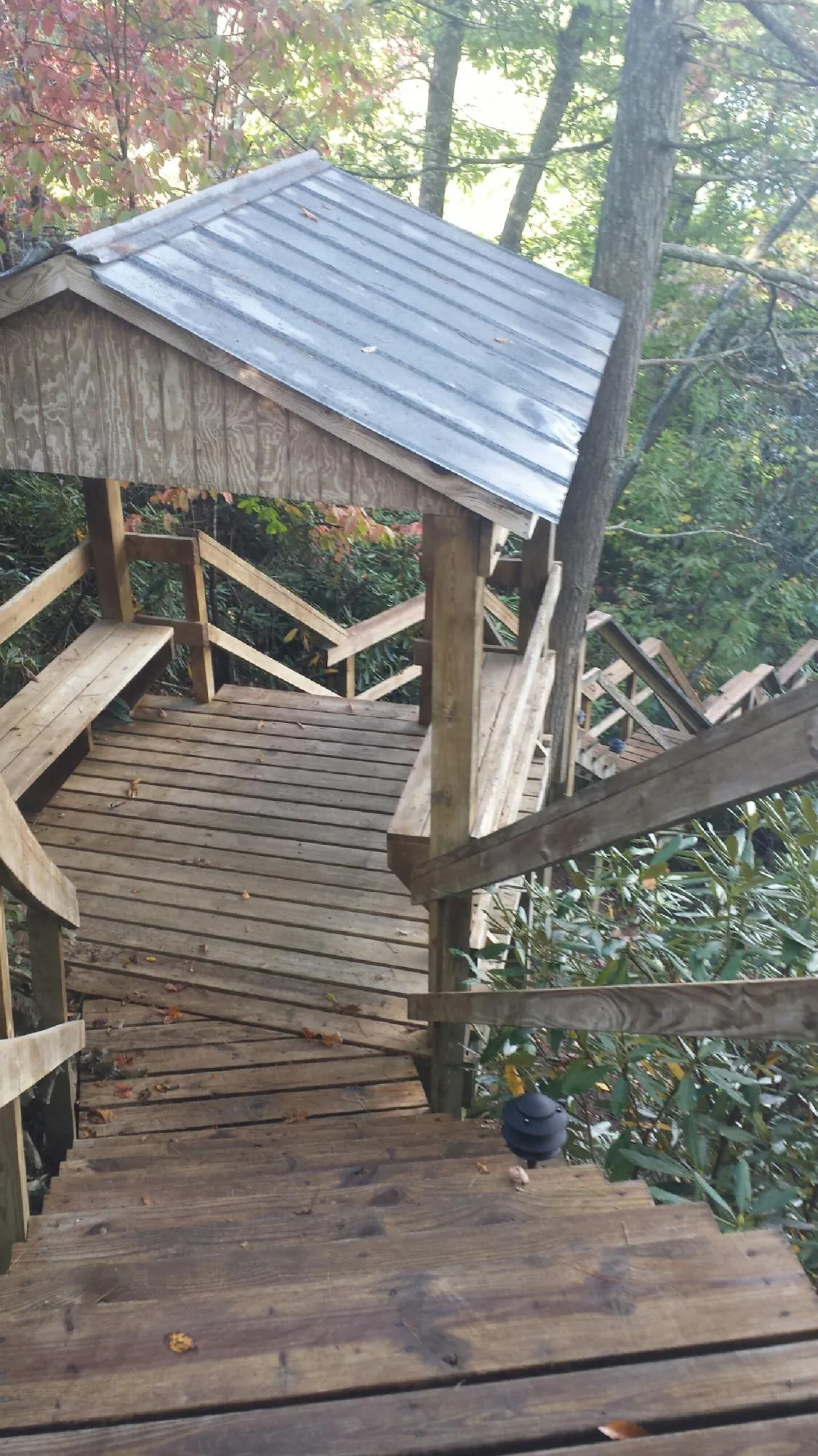 Metal roofed shelter over wooden steps on a wooded walkway — Skylight Repair & Installation work by our crew in Santa Claus