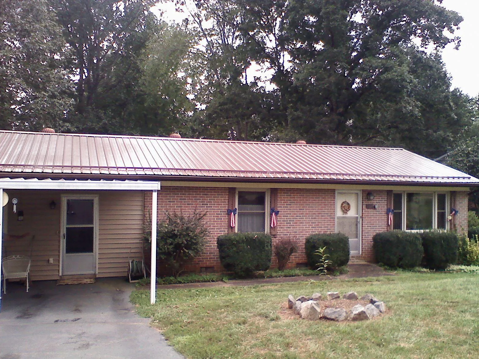 Bronze metal roof and carport on a brick ranch home — Roof Repair work by our crew in Santa Claus