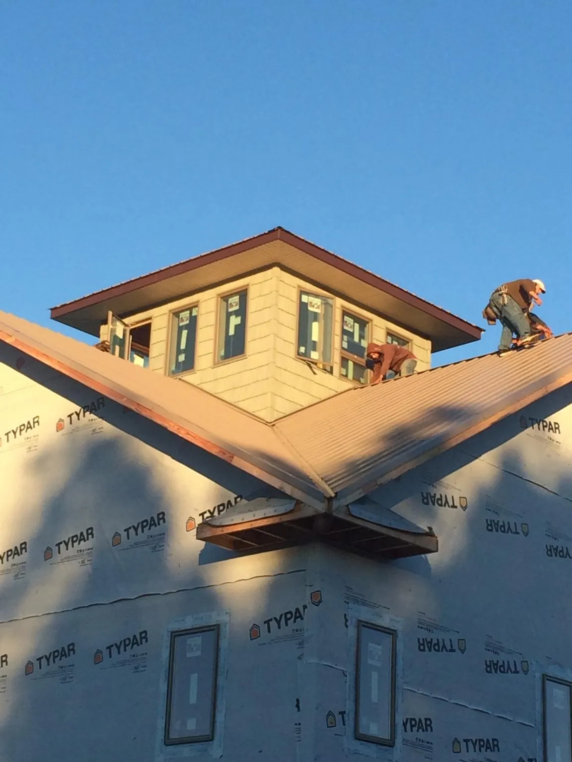 Roofers working around a rooftop cupola on a new metal roof at sunset — Roof Waterproofing in Santa Claus by Roofing Brothers